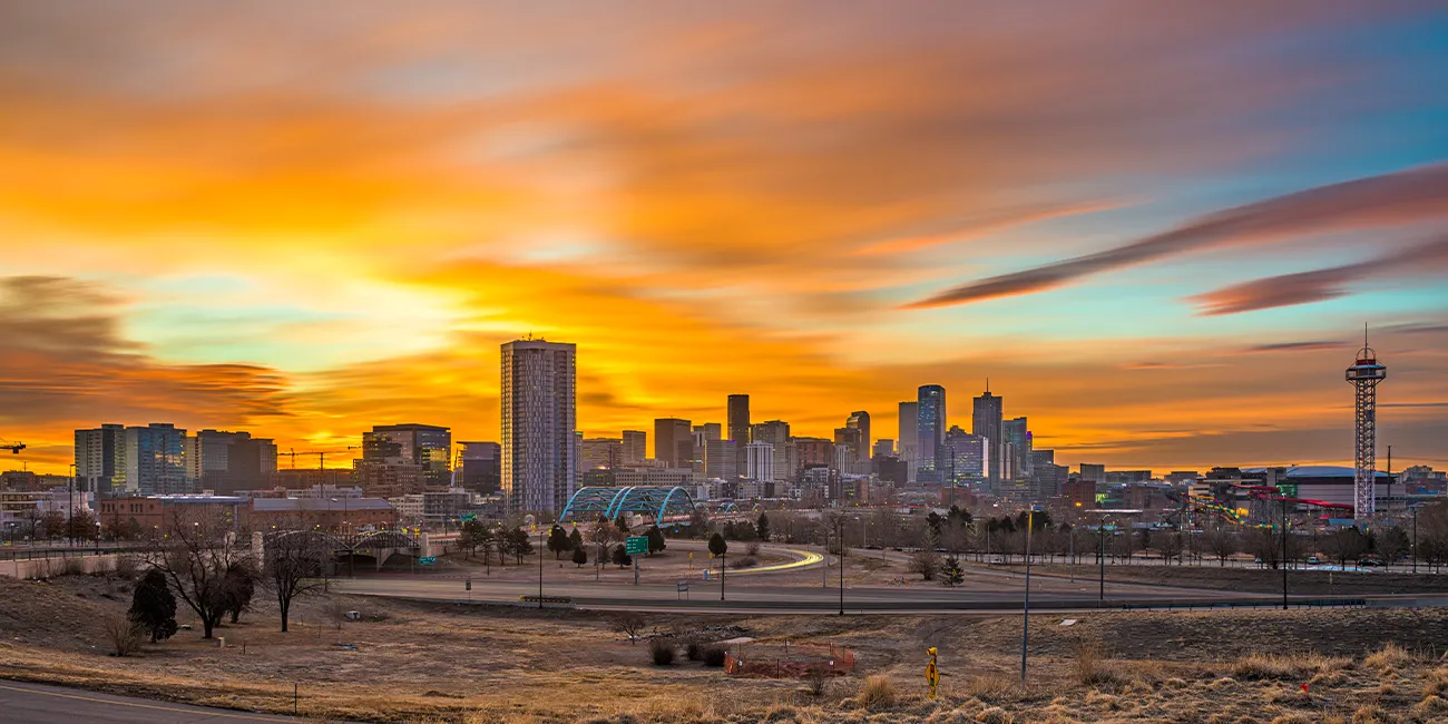 A colorful, orange sunrise lights up the Denver, CO skyline.