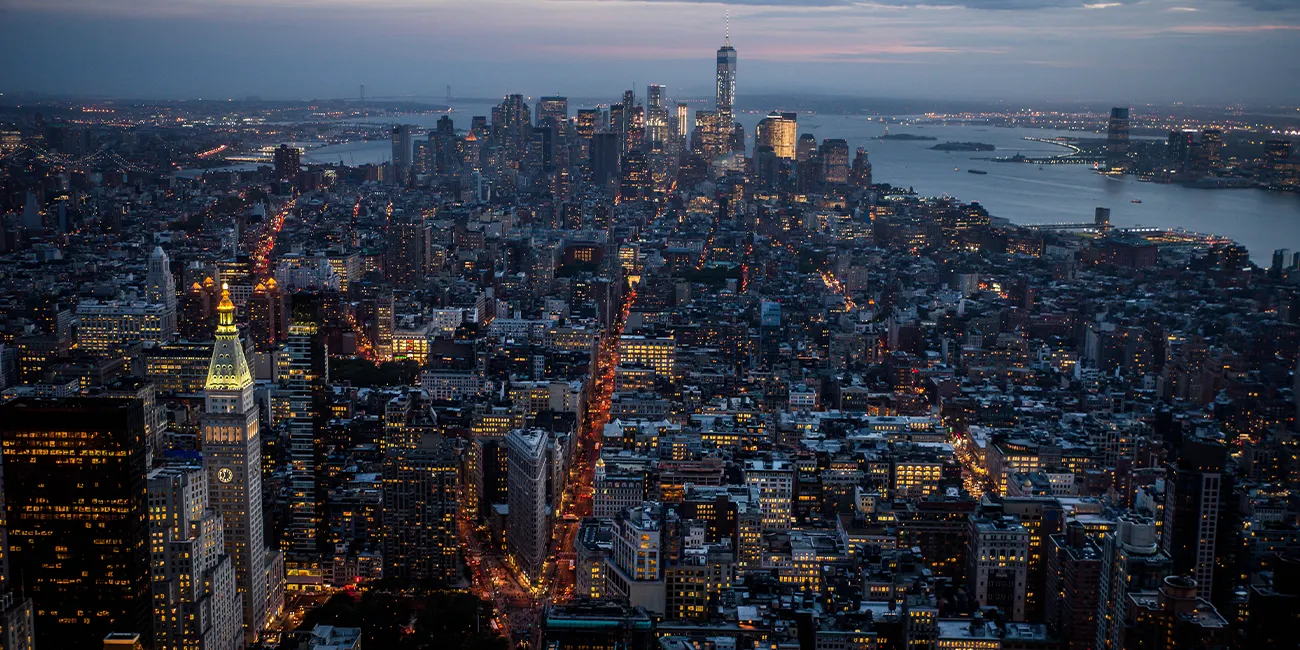 A sprawling aerial view of New York City at dusk, with thousands of lights seen all across the crowded cityscape.
