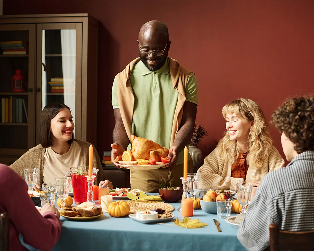 A man places a turkey at a Thanksgiving meal