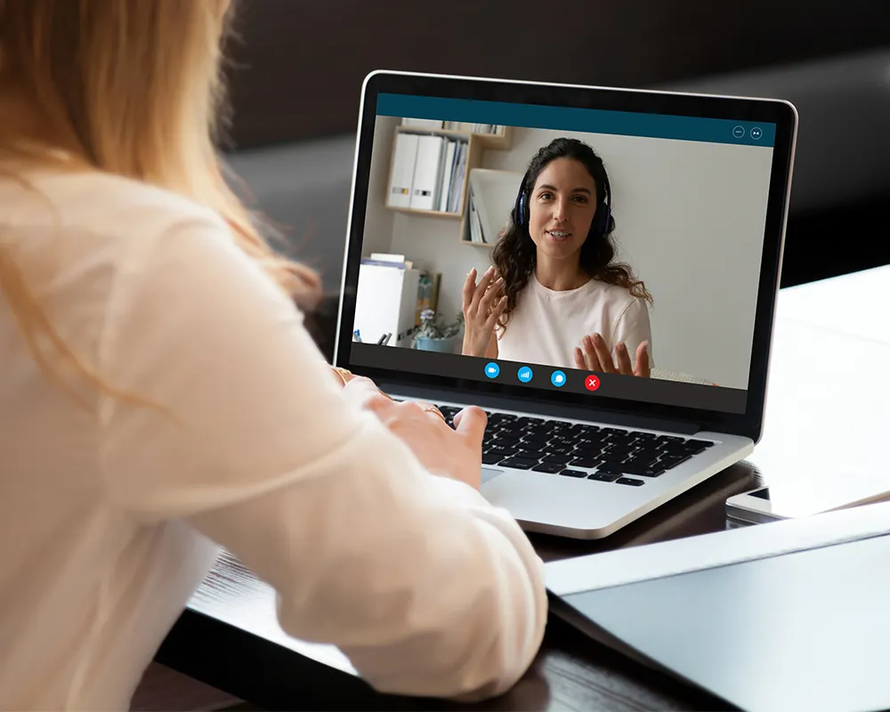 A professional woman speaks to another business person over a video chat