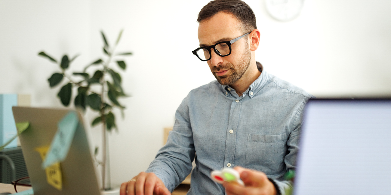 Man at his desk playing with a fidget toy while working