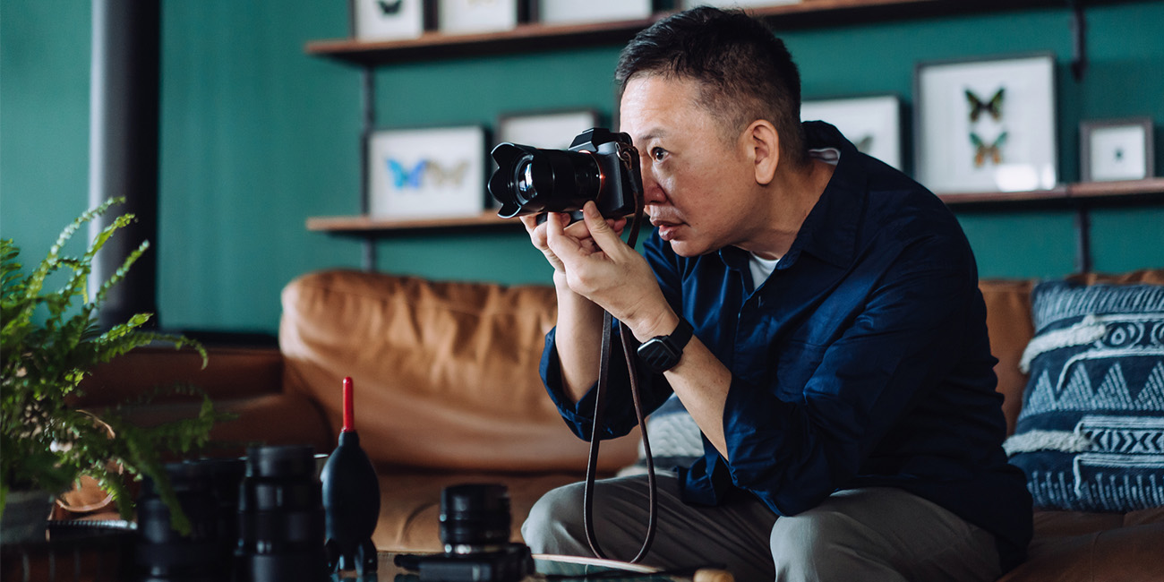 A man sitting on the couch messing with his camera