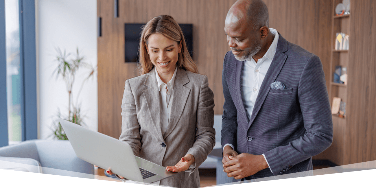 Two coworkers standing next to each other while looking at a laptop