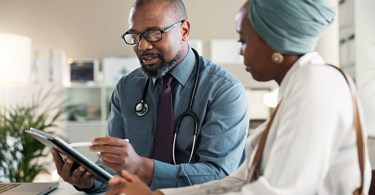 Healthcare worker talking to patient and showing something on the tablet screen.